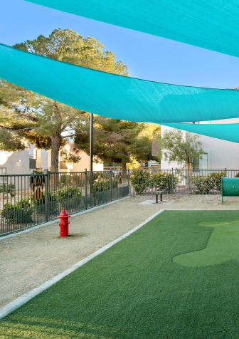 a green astroturf baseball field with a blue awning overhead
